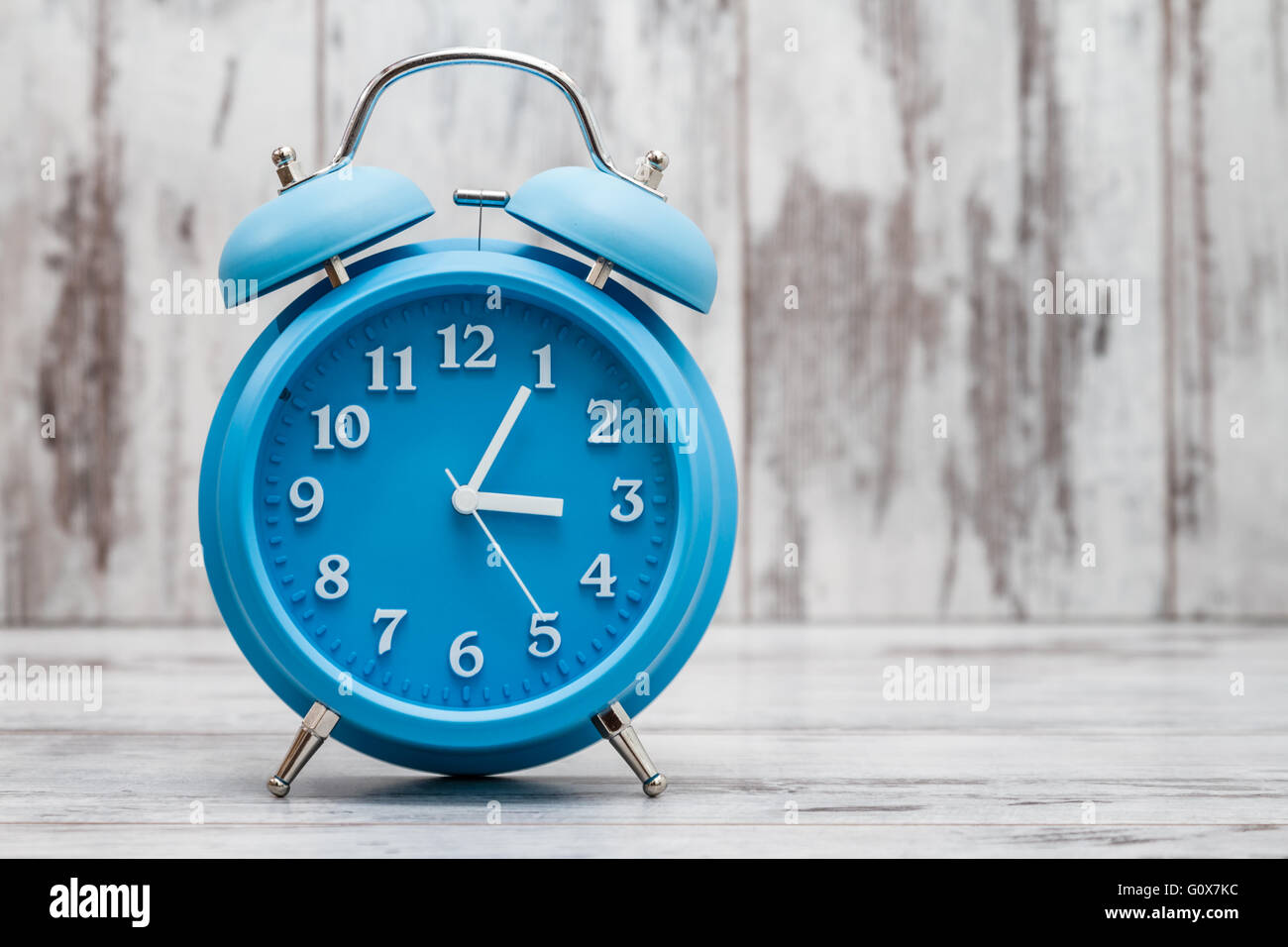 Blue retro alarm clock on white wooden background Stock Photo - Alamy