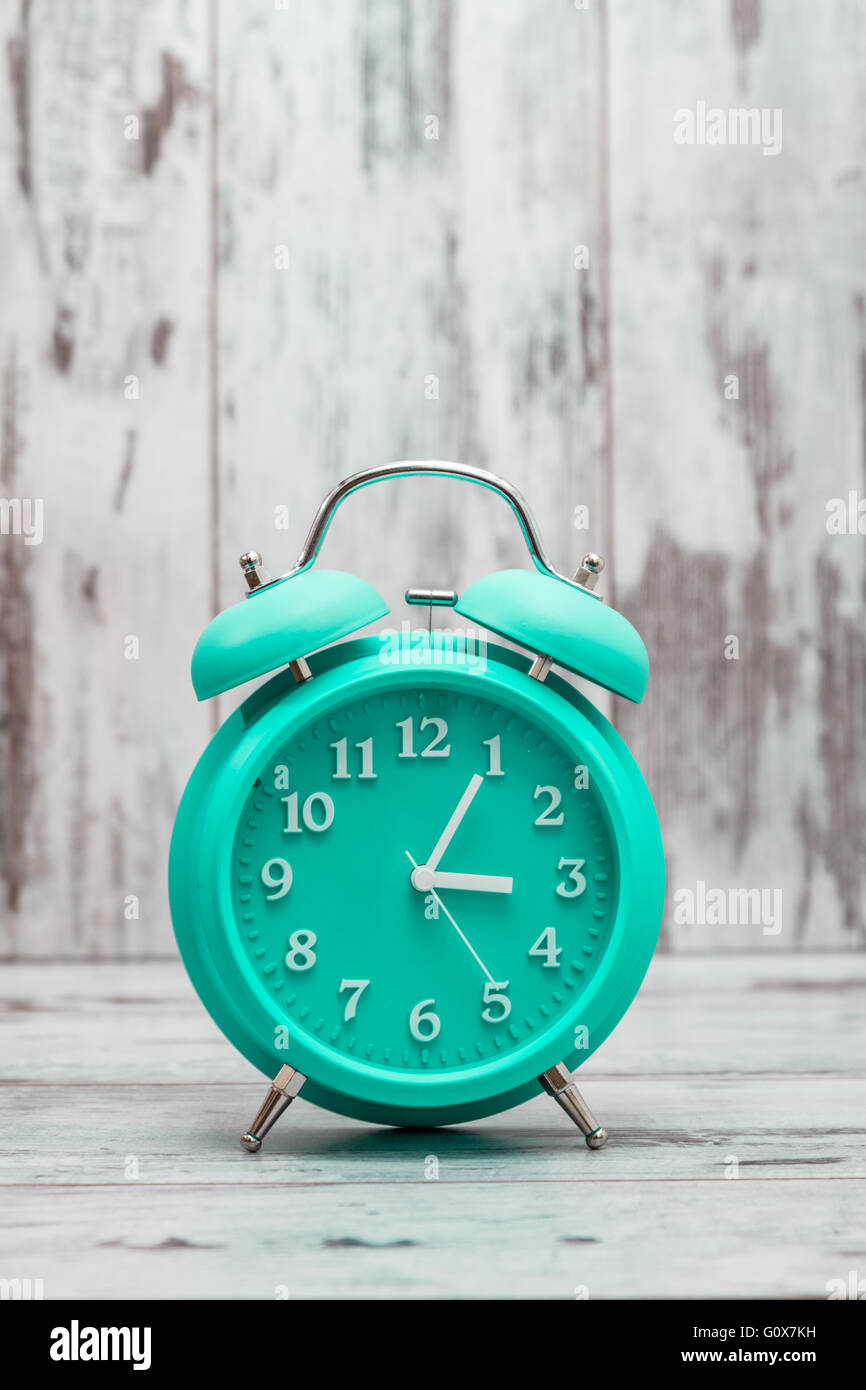 Green retro alarm clock on white wooden background Stock Photo - Alamy