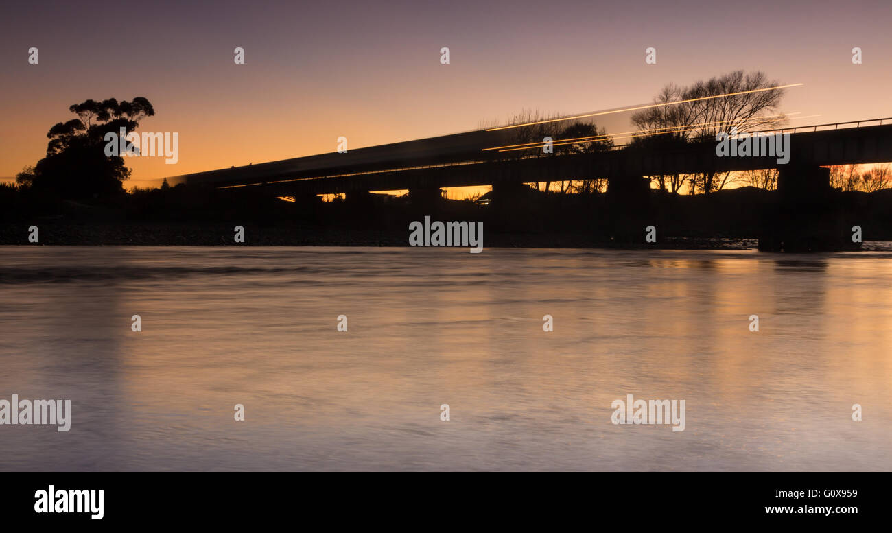 Train crossing over a river bridge at dawn. Stock Photo