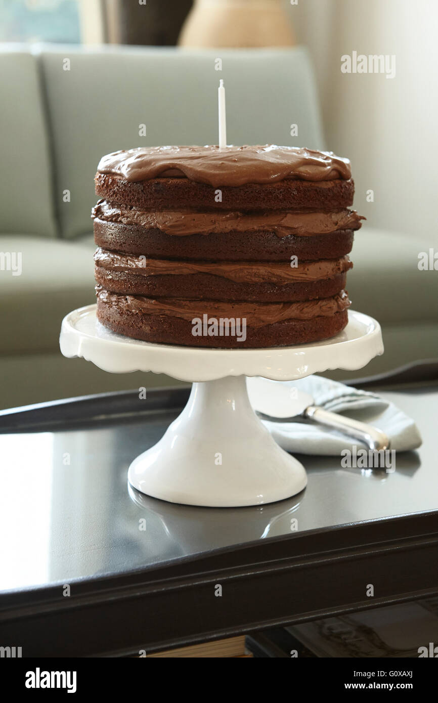 Layered Chocolate Birthday Cake with Candle on Cake Stand on Coffee