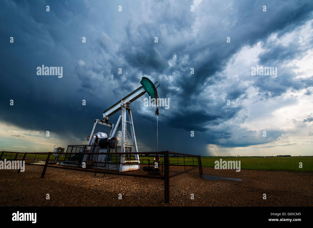 Pump jack, oil well, in field with stormy sky, Canadian praires, Saskatchewan, Canada Stock Photo