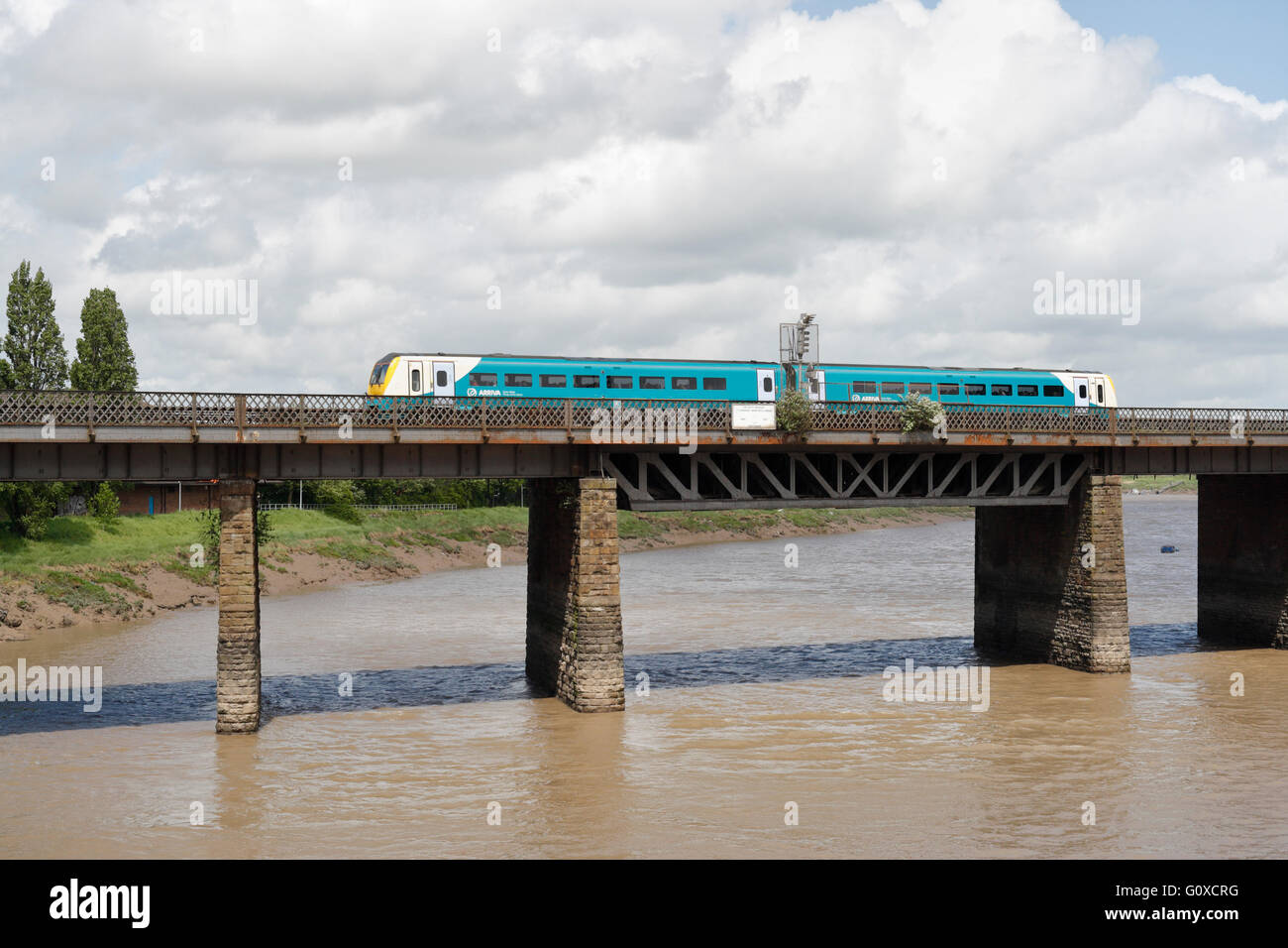 The River Usk in Newport Wales, with Arriva commuter train passing over.. Railway bridge structure Stock Photo