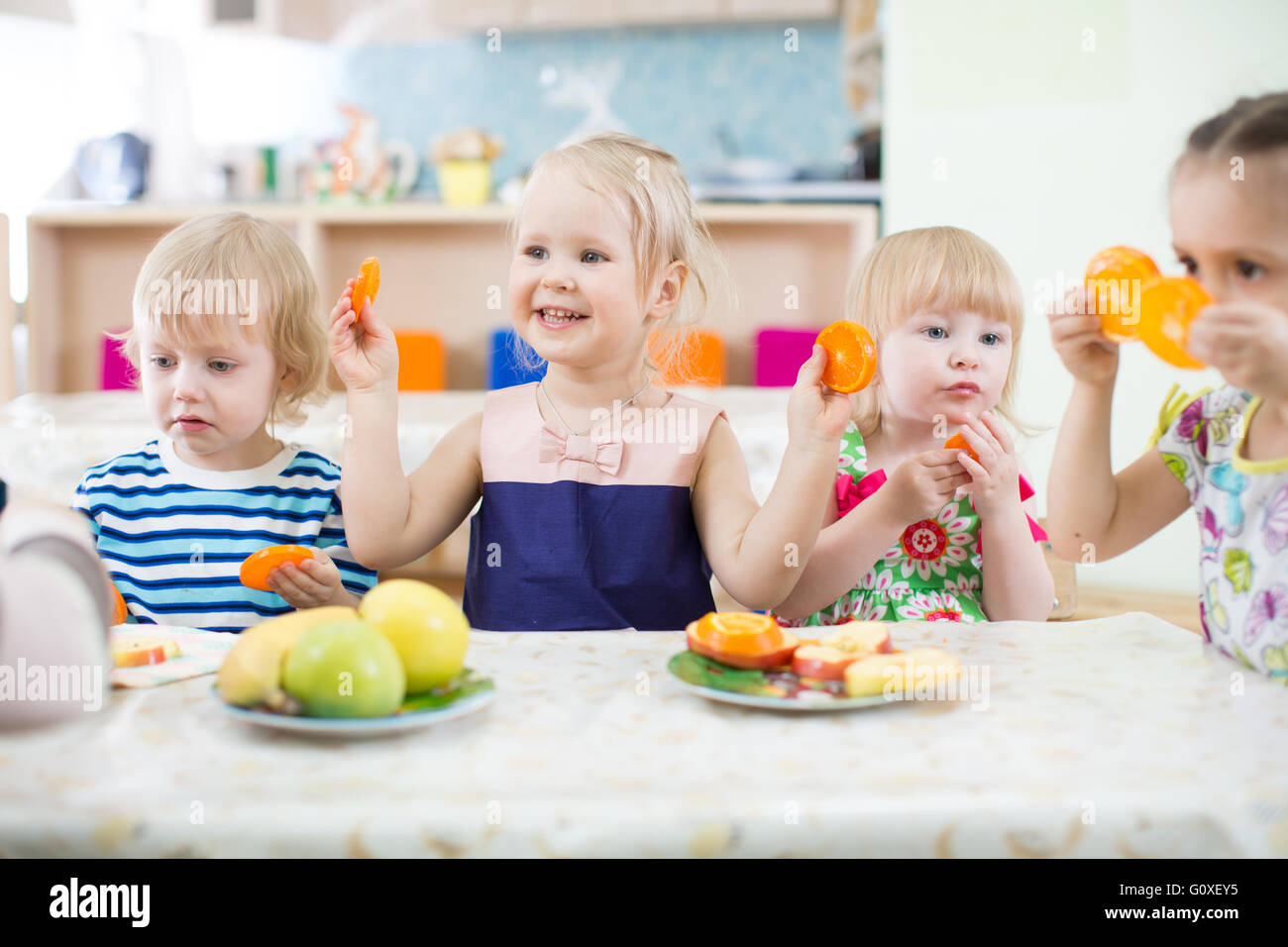 Funny kids eating fruits in day care centre Stock Photo