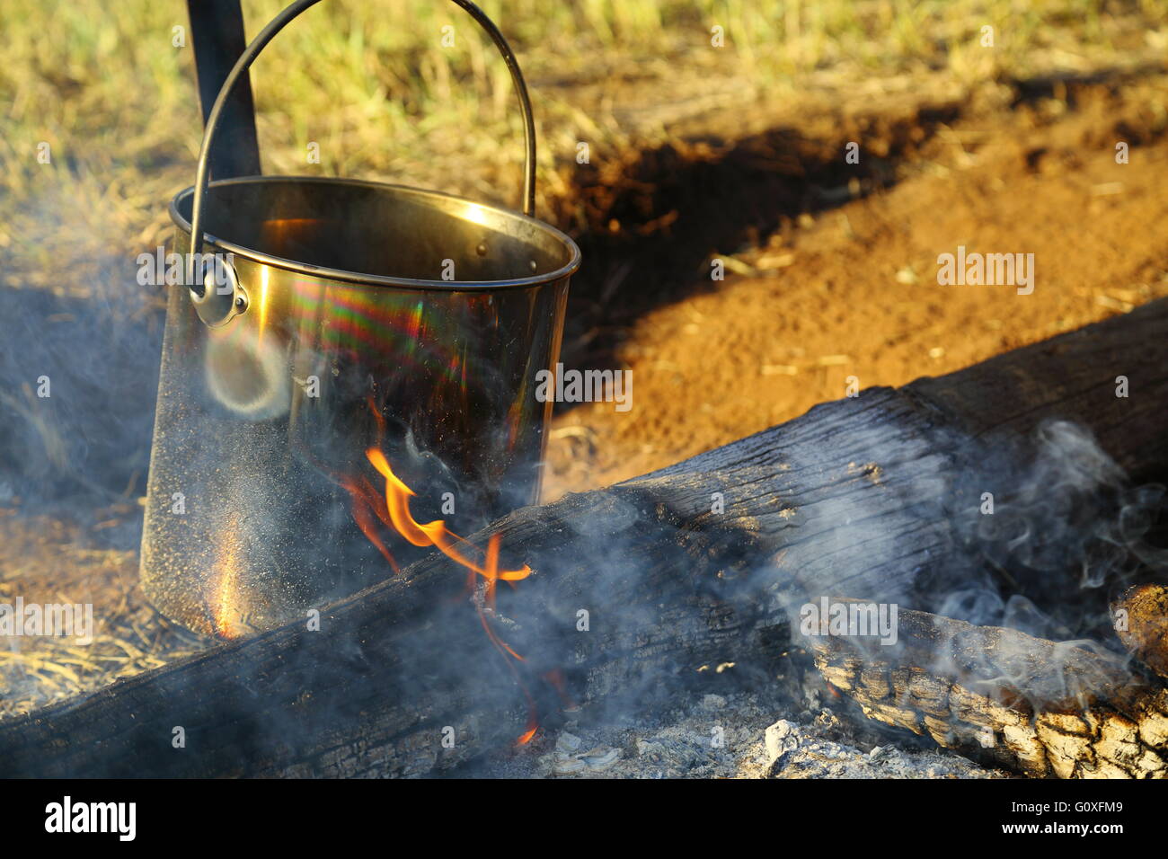 A large stainless steel cooking pot being brought to a boil in an open camp fire in Queensland, Australia. Stock Photo