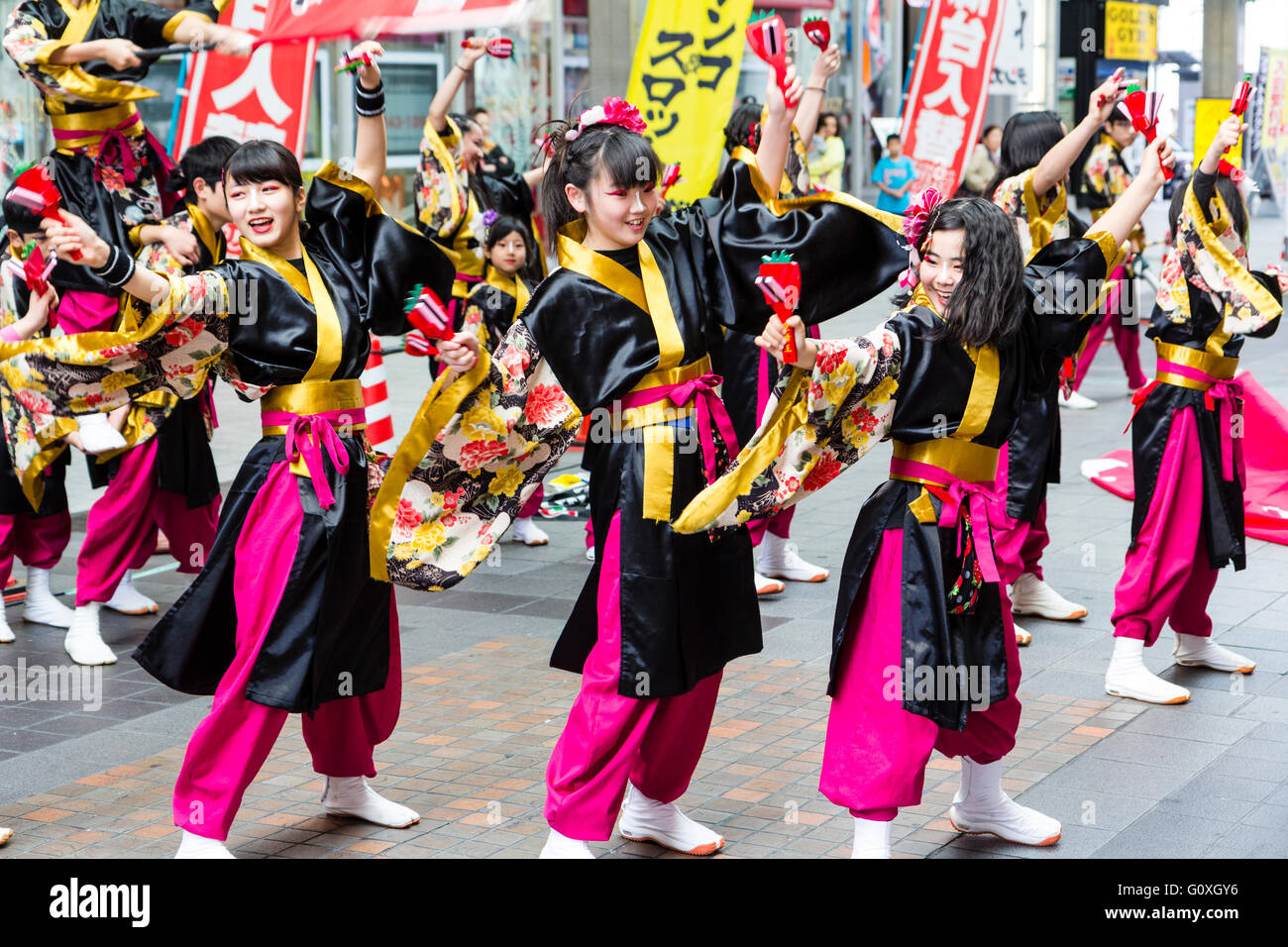 Japanese Yosakoi dance festival. Rows of Children dancing while holding naruko, wooden clappers, and wearing black yukata and purple trousers. Stock Photo