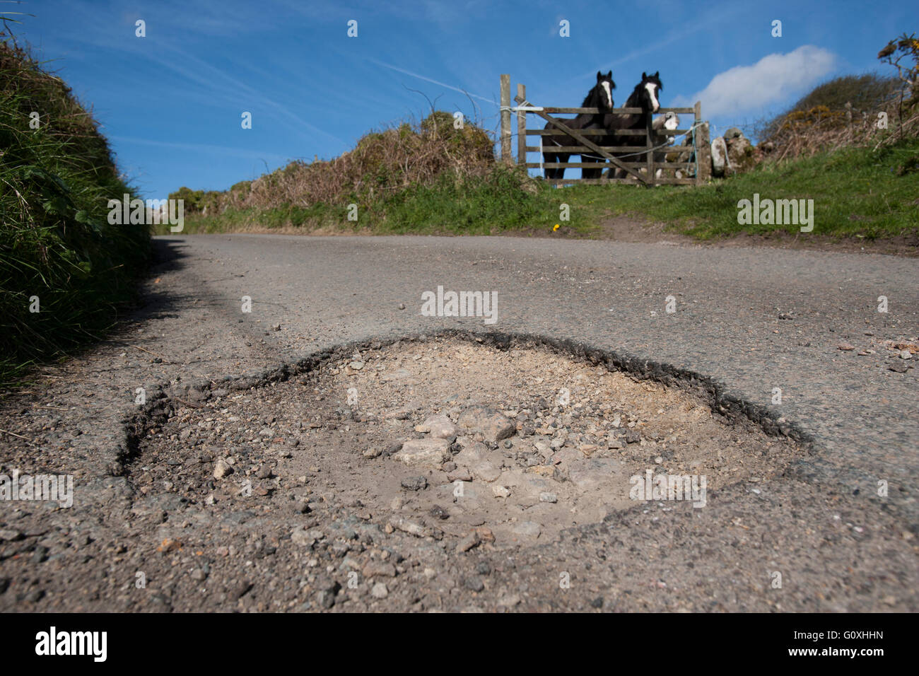 Countryside potholes in the road cause damage to cars and are a danger to unsuspecting motorcyclists and cyclists pot hole Stock Photo