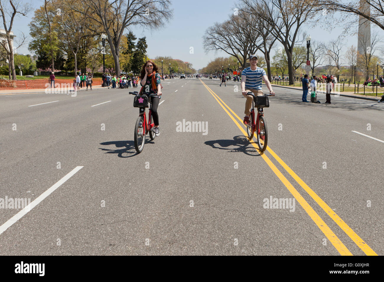 A couple riding their bikes in the middle of the road - Washington DC USA Stock Photo