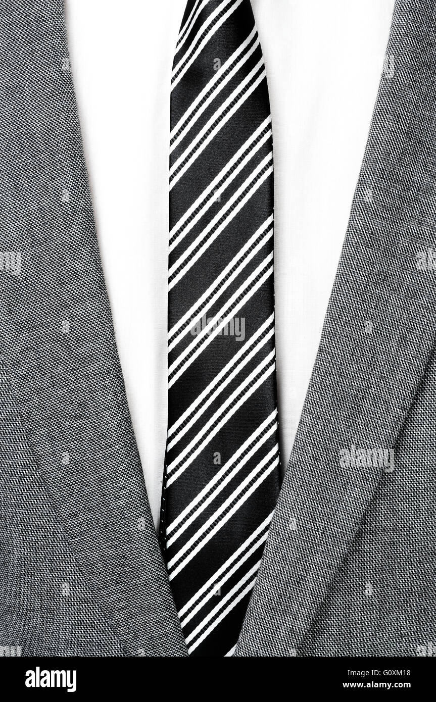 detail of a man wearing a gray jacket suit, white shirt and black and white striped tie Stock Photo