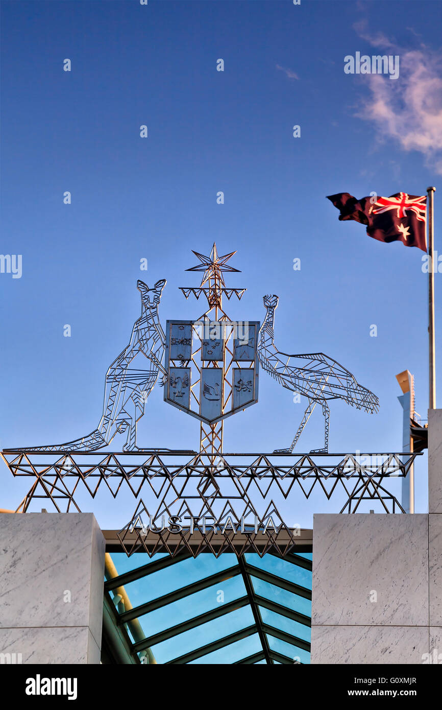 Coats of arms and national flag on top of modern Parliament House at Capital hill in Canberra, ACT. Blue sky behind national sym Stock Photo