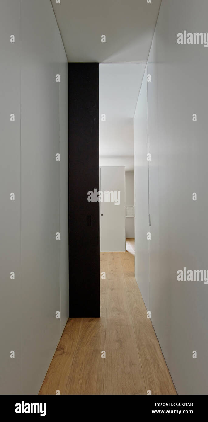 View of a narrow modern hallway with white walls and wood floor. Stock Photo