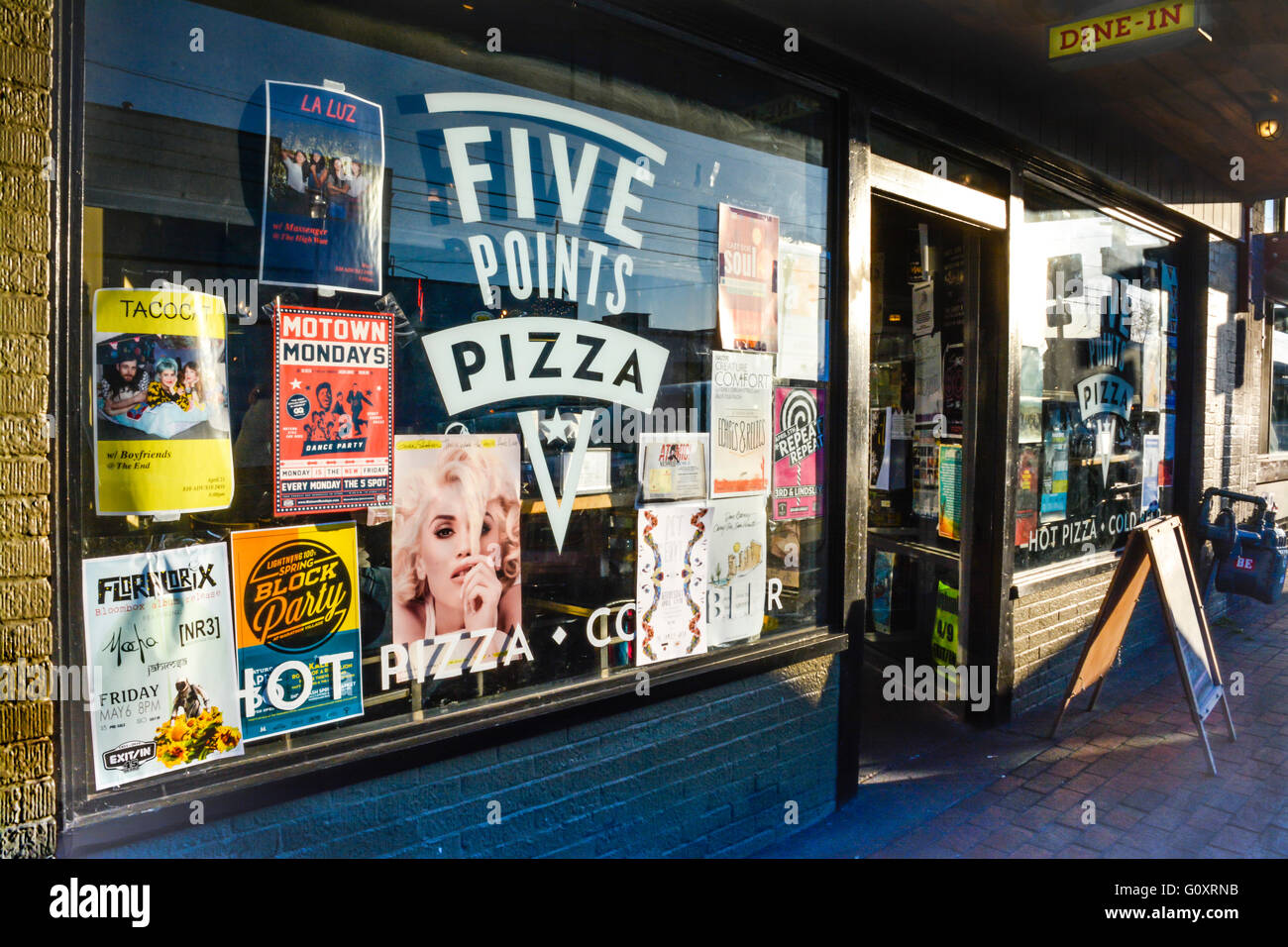 Posters cover the glass Storefront at sunset at Five Points Pizza in the trendy neighborhood in East Nashville, TN Stock Photo