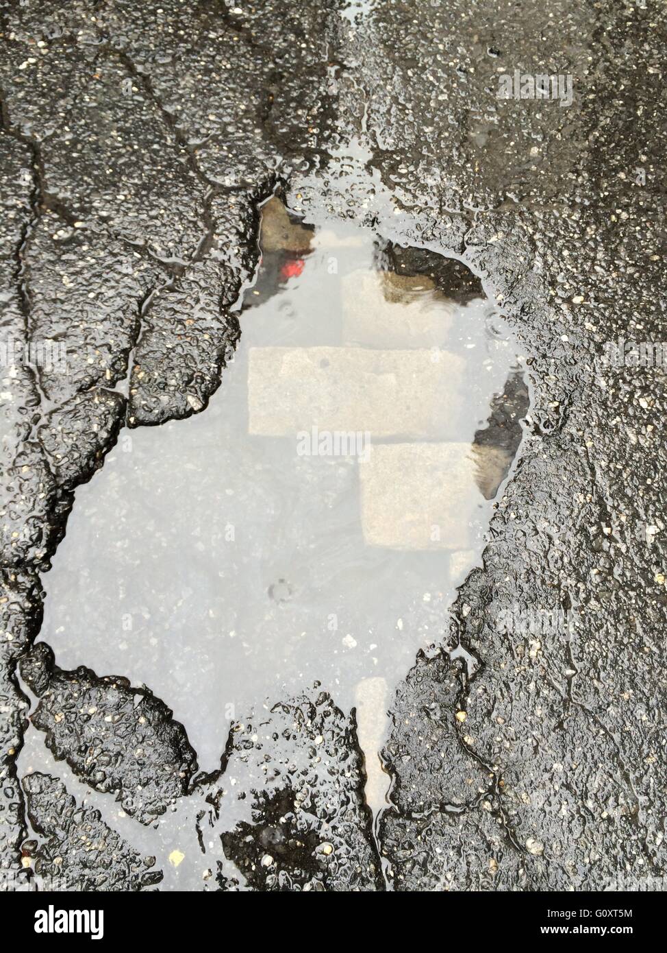 Old brick peering through a pothole in the asphalt of a Tribeca street in NYC. Stock Photo