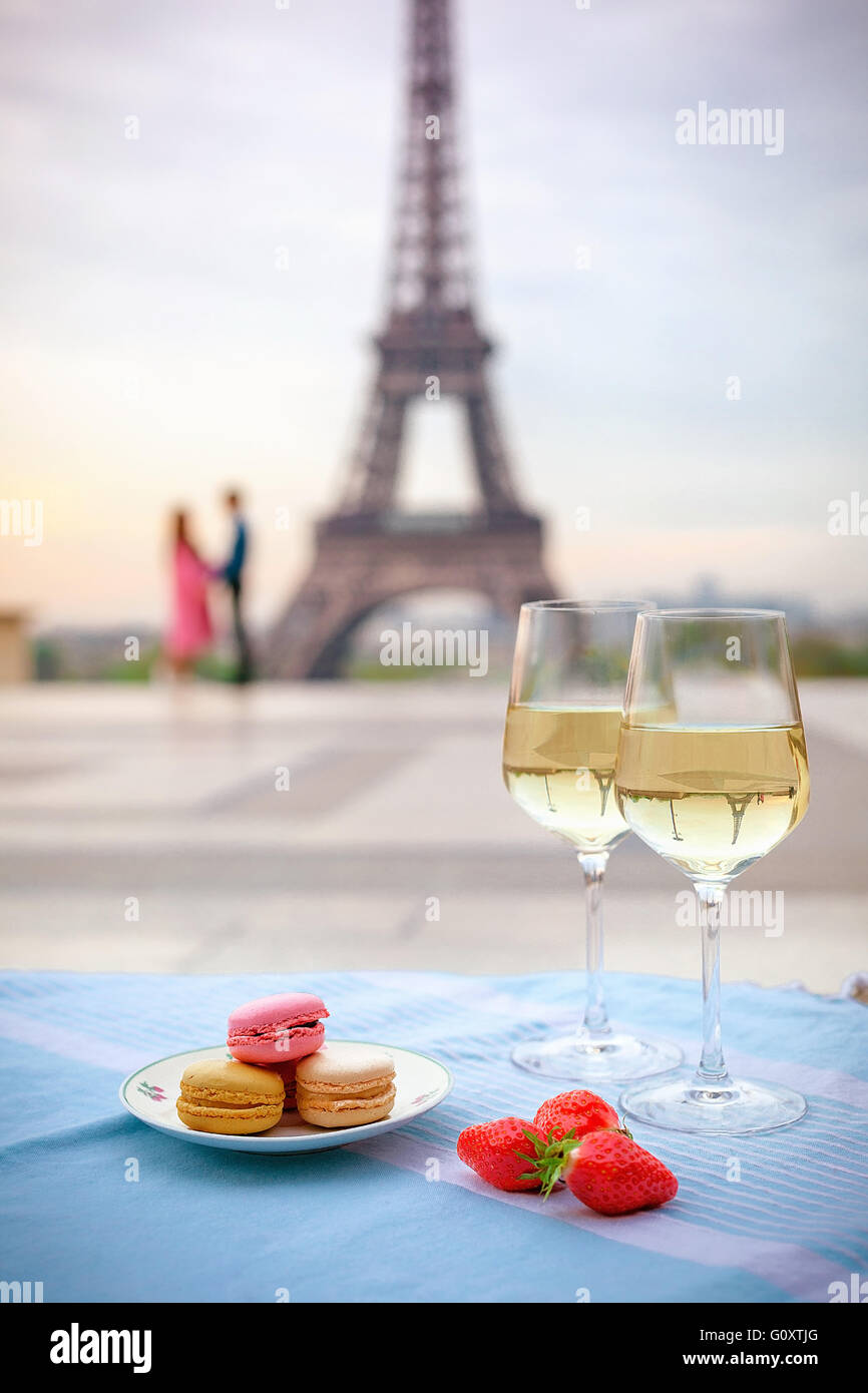 Composition of wine glasses, flowers and macaroons with the view for Eiffel tower in Paris spring Stock Photo