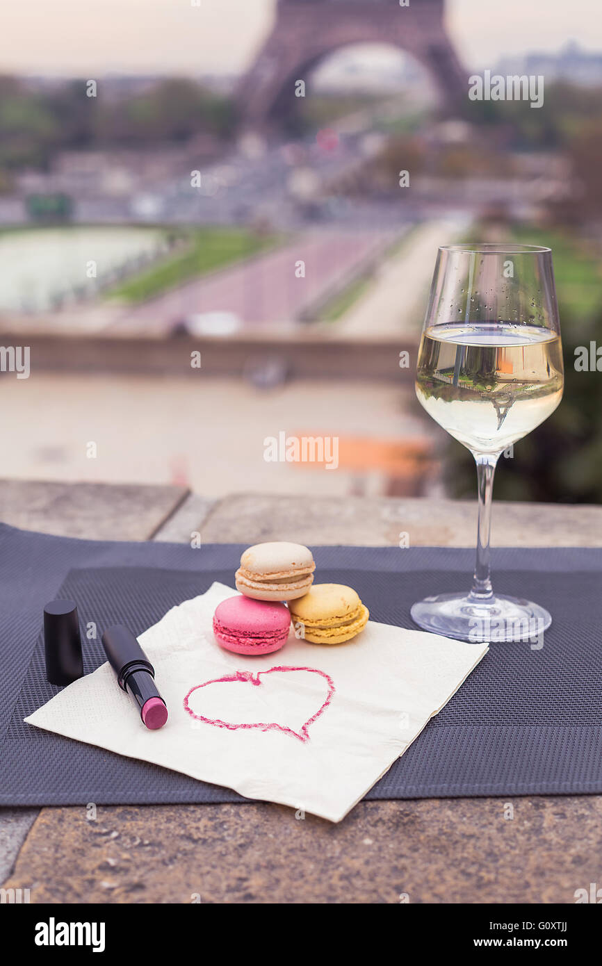 Composition of wine glasses, flowers and macaroons with the view for Eiffel tower in Paris spring Stock Photo
