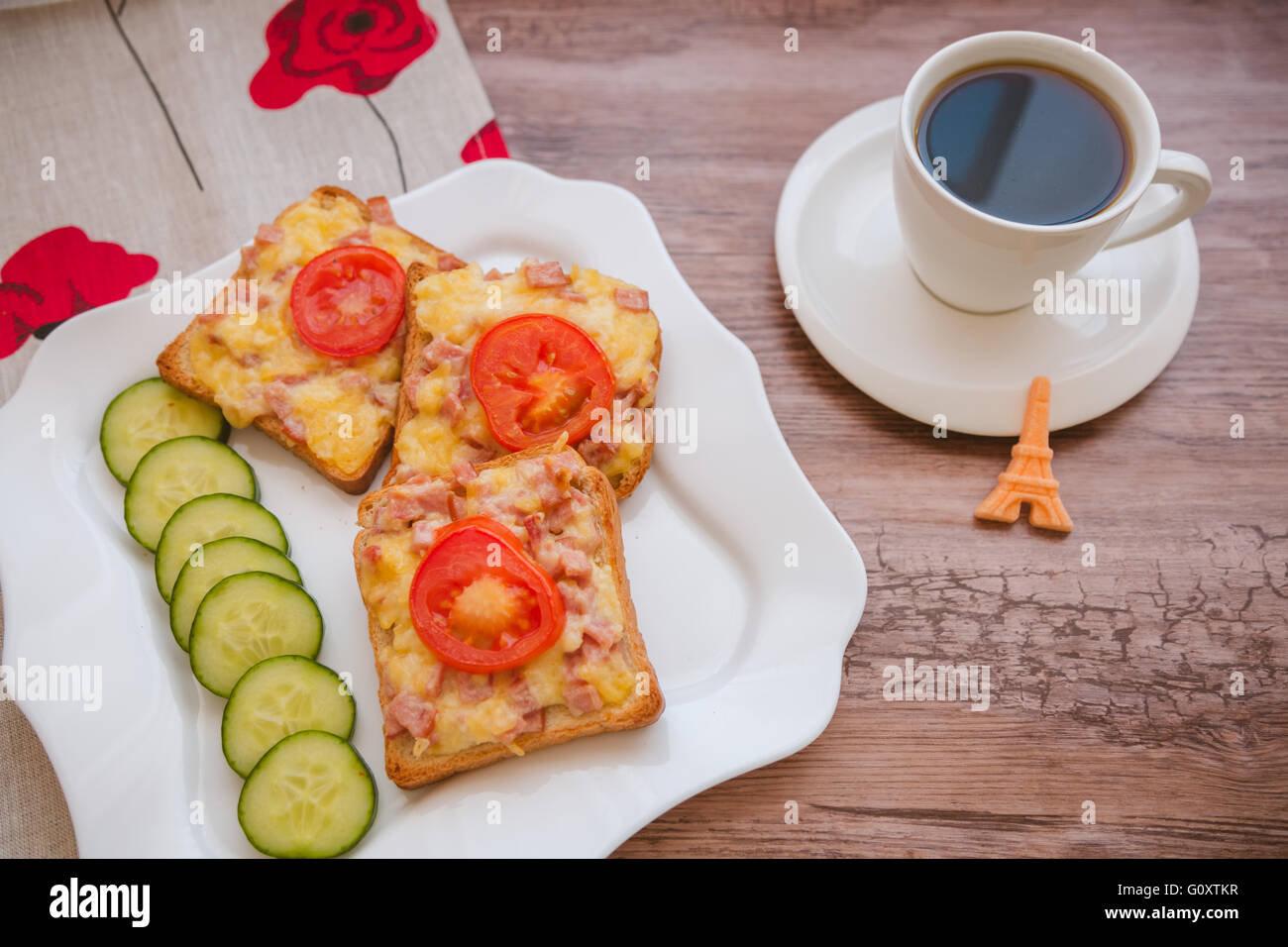 Morning breakfast: homemade toasted open sandwich with ham and cheese, coffee and fresh vegetables on wooden background Stock Photo