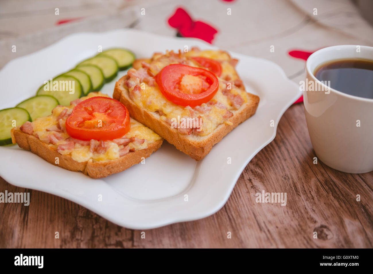 Morning breakfast: homemade toasted open sandwich with ham and cheese, coffee and fresh vegetables on wooden background Stock Photo