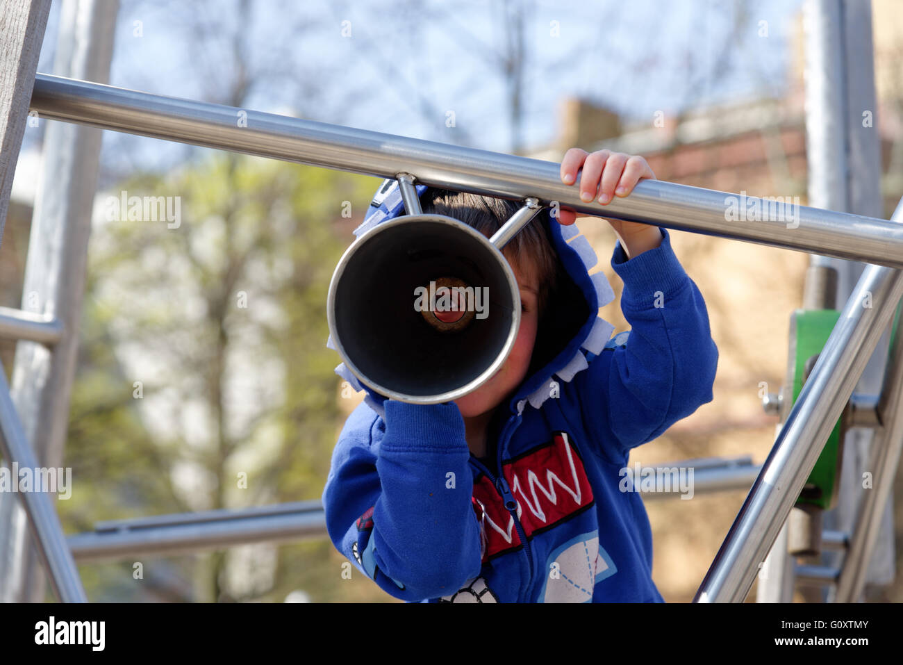 A young boy (4 years old) looking through a play telescope Stock Photo