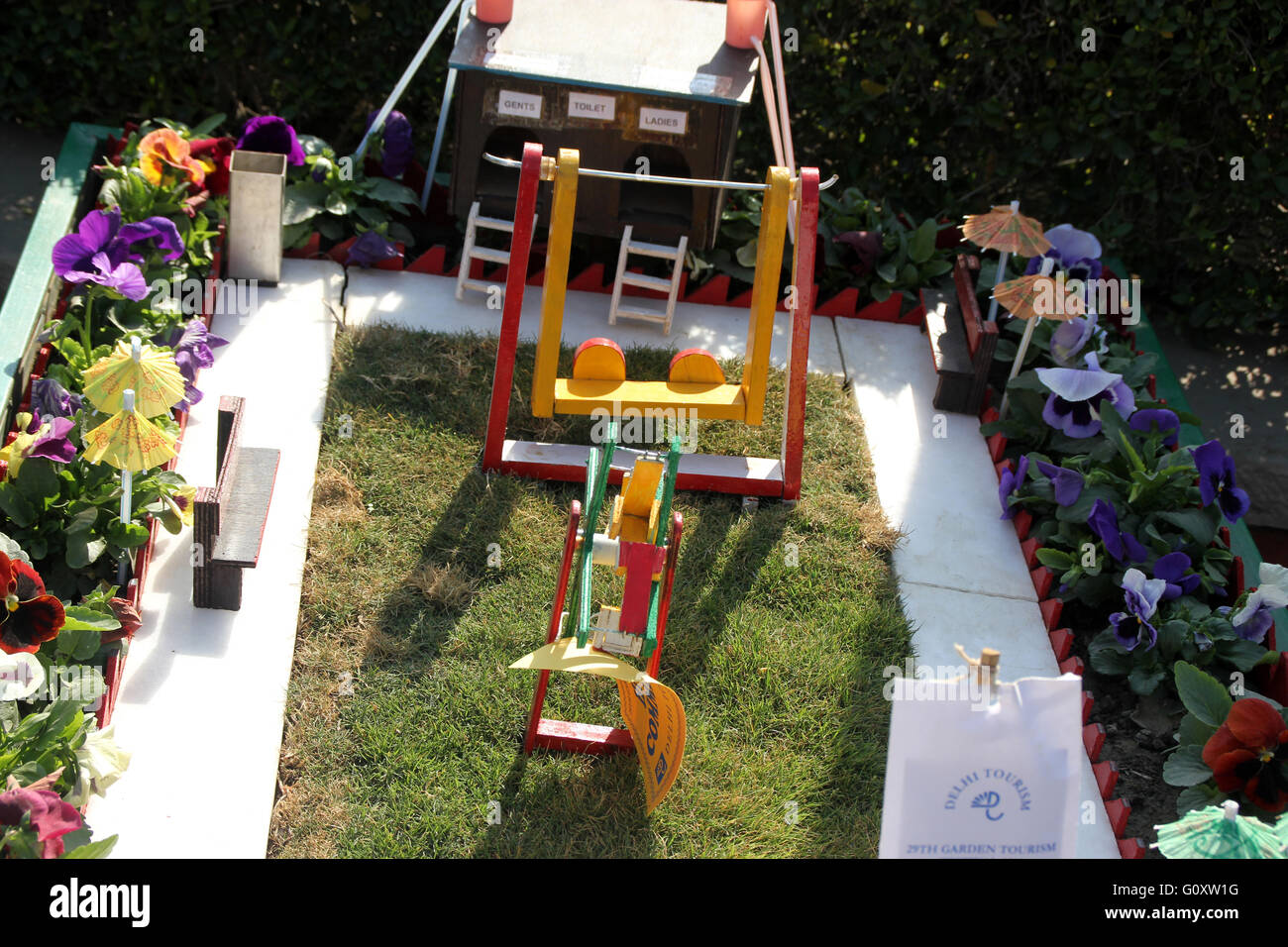 Mini garden on a cart displayed at Garden Festival, complete with lawn, swings, umbrellas, foliage plants and garden annuals Stock Photo