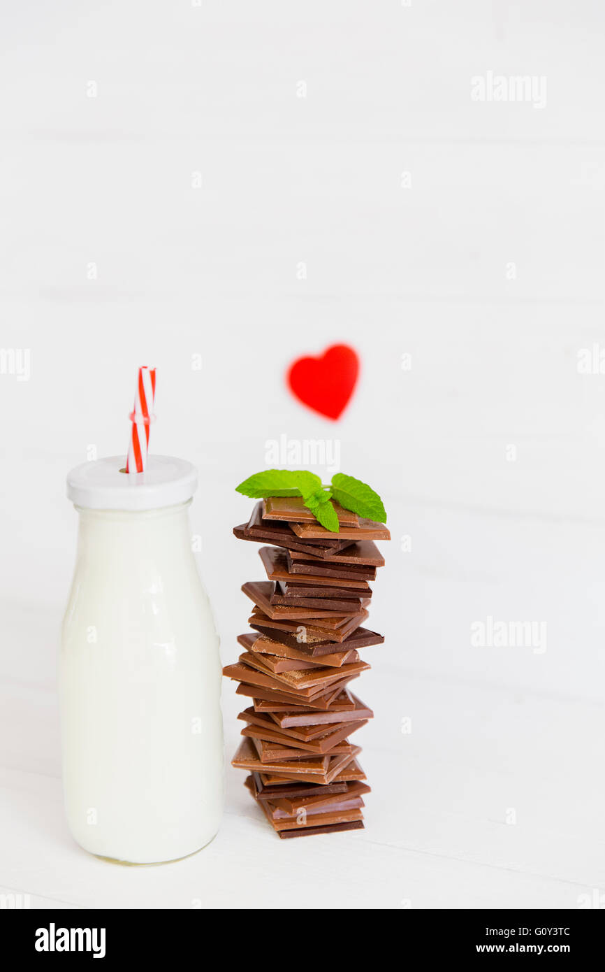 Bottle of milk with stack of chocolate and heart shape Stock Photo