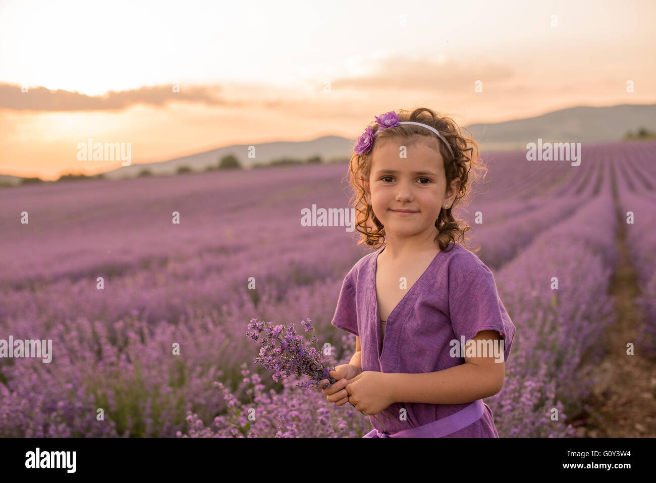 Girl standing in lavender flower field at sunset, Kazanlak, Bulgaria Stock Photo