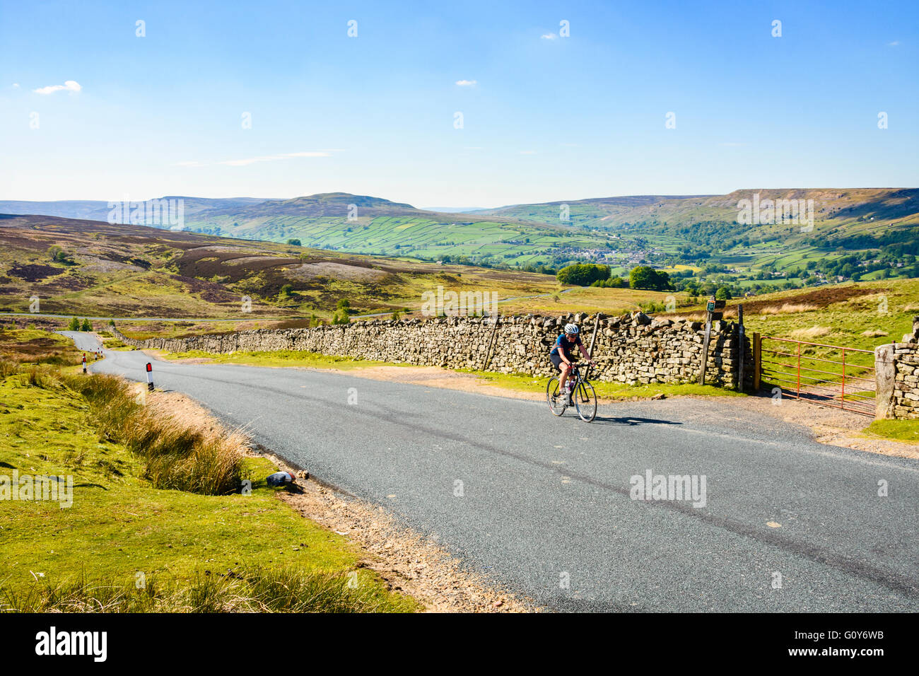 Female cyclist on the climb of Grinton Moor above Swaledale in the Yorkshire Dales Stock Photo