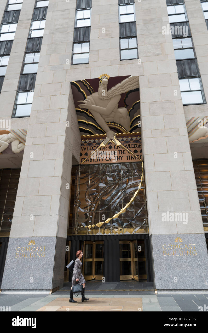 Woman walking past the front entrance of the Rockefeller Center / Comcast building in New York City with art deco relief Stock Photo