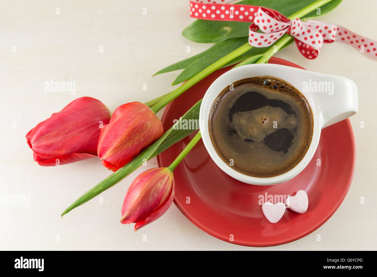 Red tulips with a cup of coffee on a wooden table Stock Photo