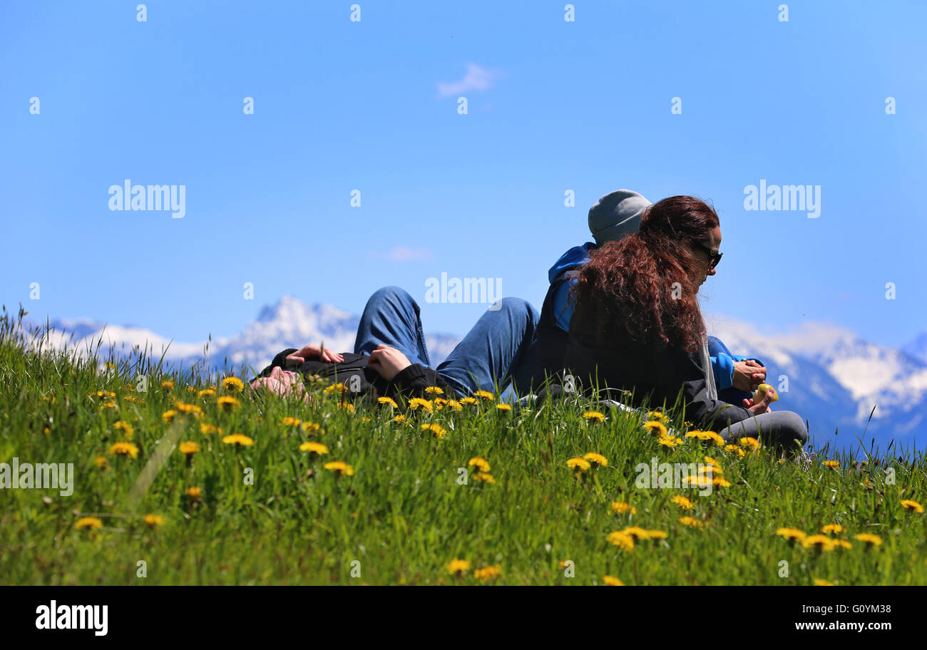 People enjoying the outdoors in a meadow on the side of a hill with a panorama view of the Alps near Seeg in Germany, 05 May 2016. Photo: Karl-Josef Hildenbrand /dpa Stock Photo
