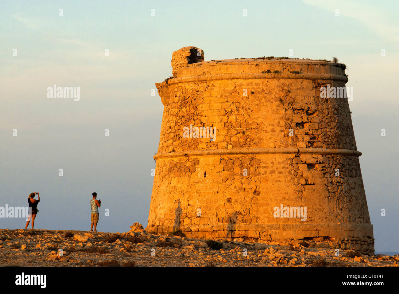 Garroveret Tower on suntet. A couple of tourist taken pictures in Torre des Garroveret - one of the towers on Formentera, Balearic Islands, Spain. Stock Photo