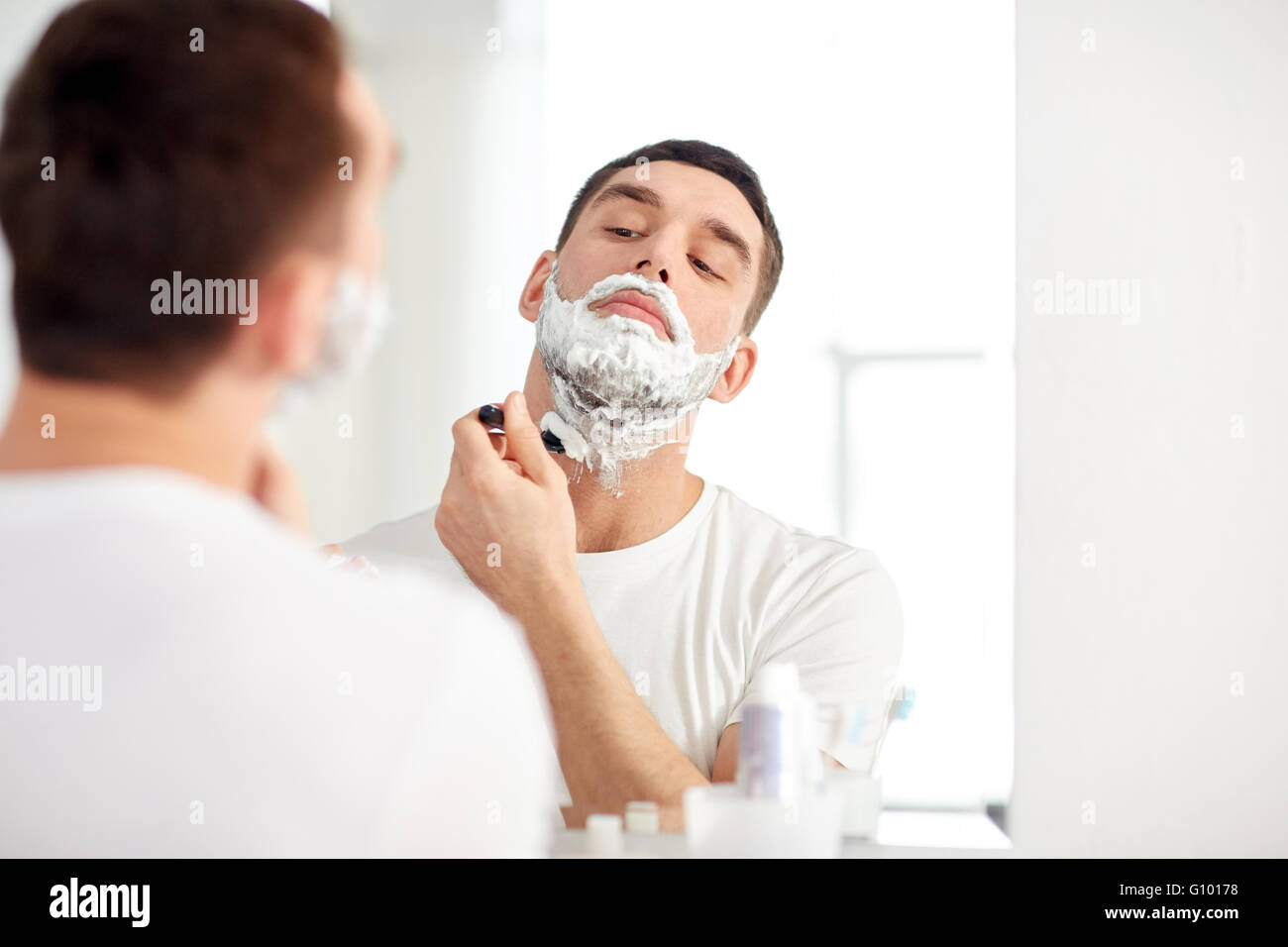 man shaving beard with razor blade at bathroom Stock Photo Alamy