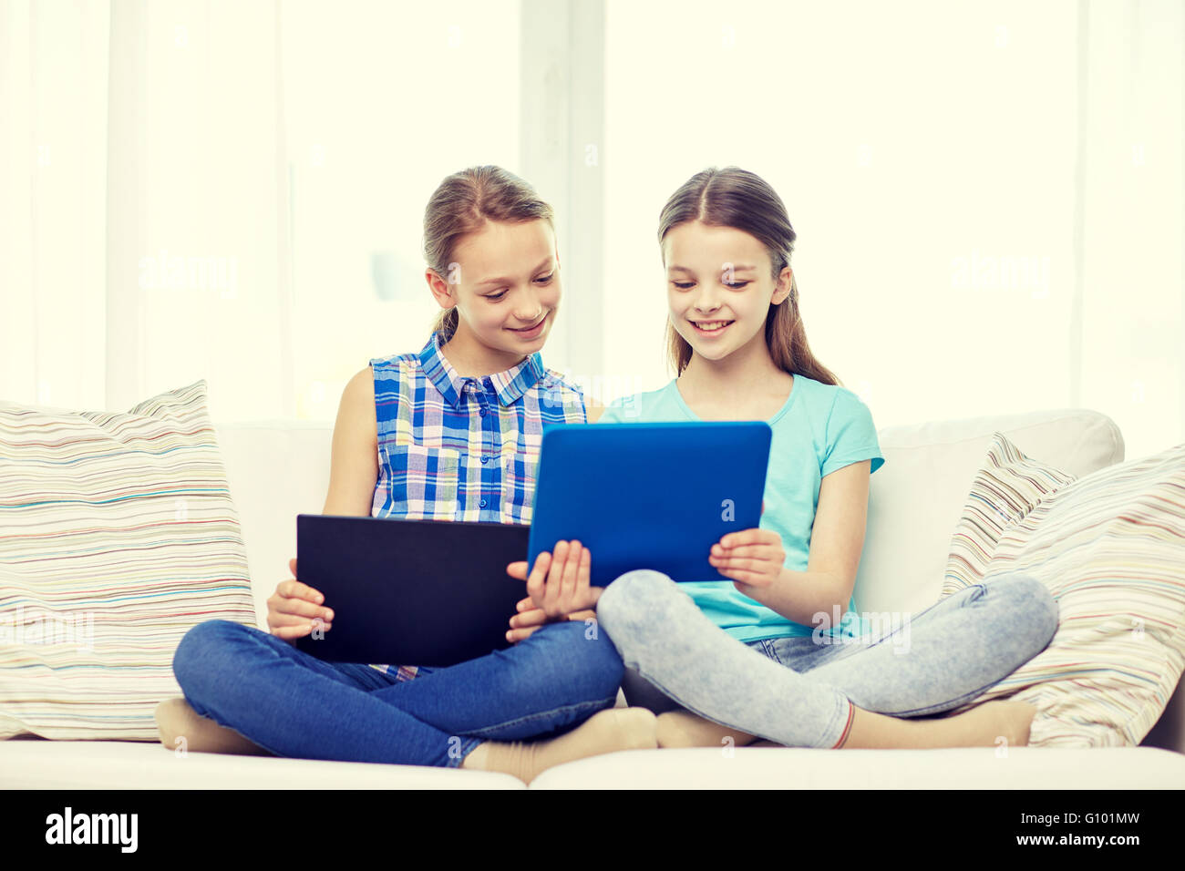happy girls with tablet pc sitting on sofa at home Stock Photo - Alamy