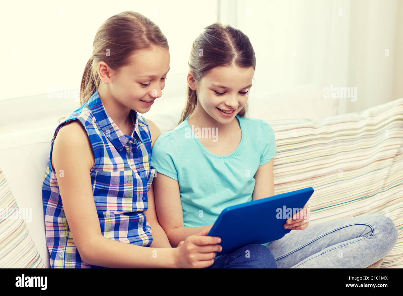 happy girls with tablet pc sitting on sofa at home Stock Photo - Alamy