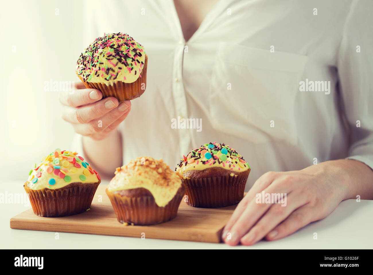 close up of woman with glazed cupcakes or muffins Stock Photo