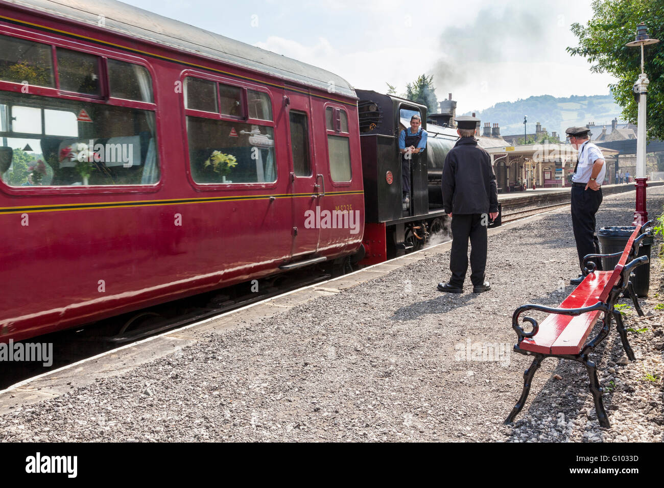 Volunteer workers for Peak Rail, a heritage railway, watch as a steam train is departing at Matlock Railway Station, Derbyshire, UK Stock Photo