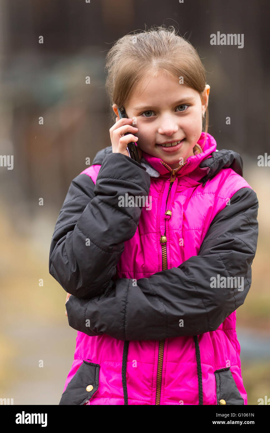 Funny little girl talking on the phone, outdoors portrait. Stock Photo