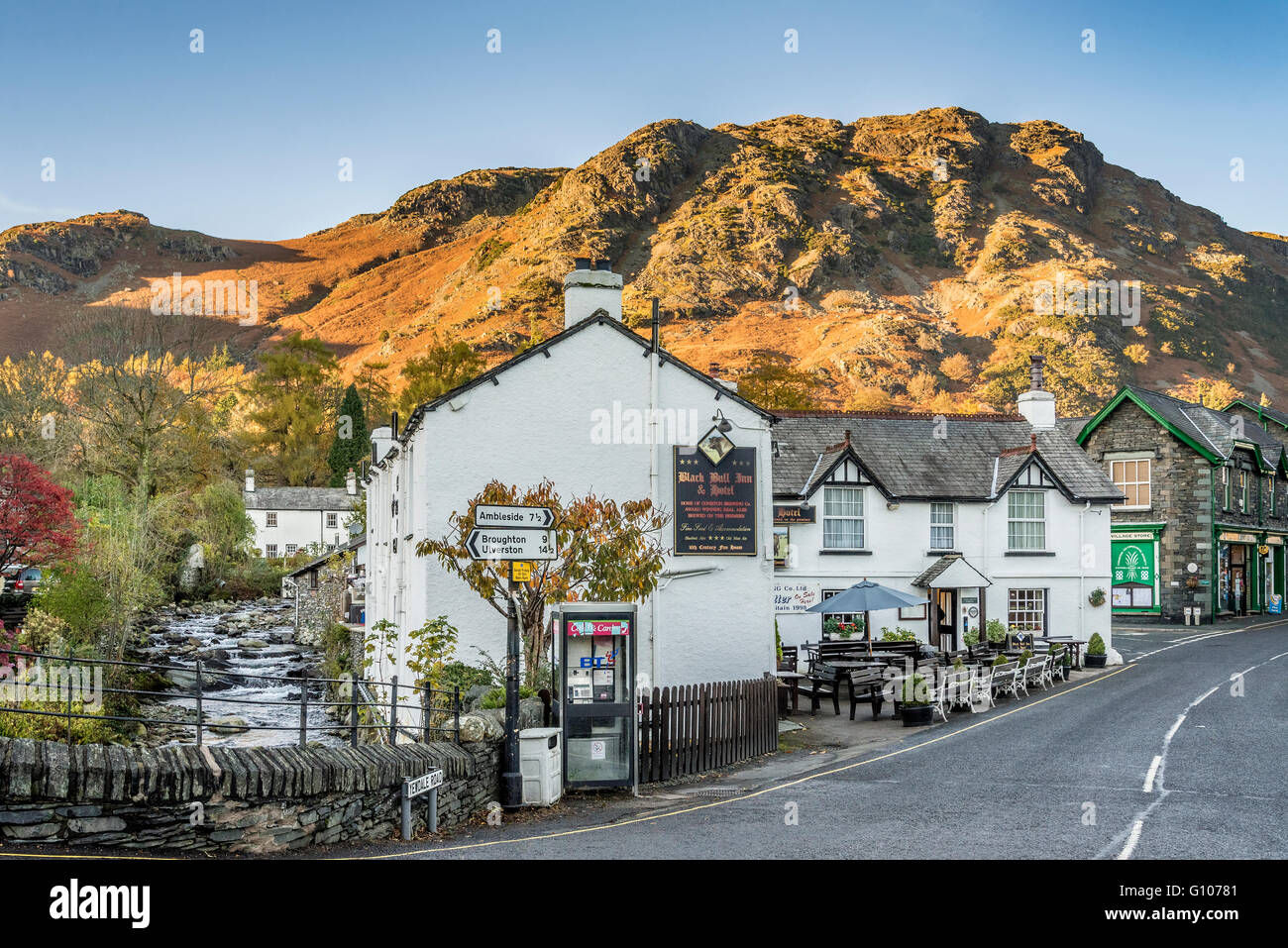 Coniston village in the Lake district of Cumbria. Evening autumn. The Black Bull Inn and hotel. North West England. stream beck Stock Photo