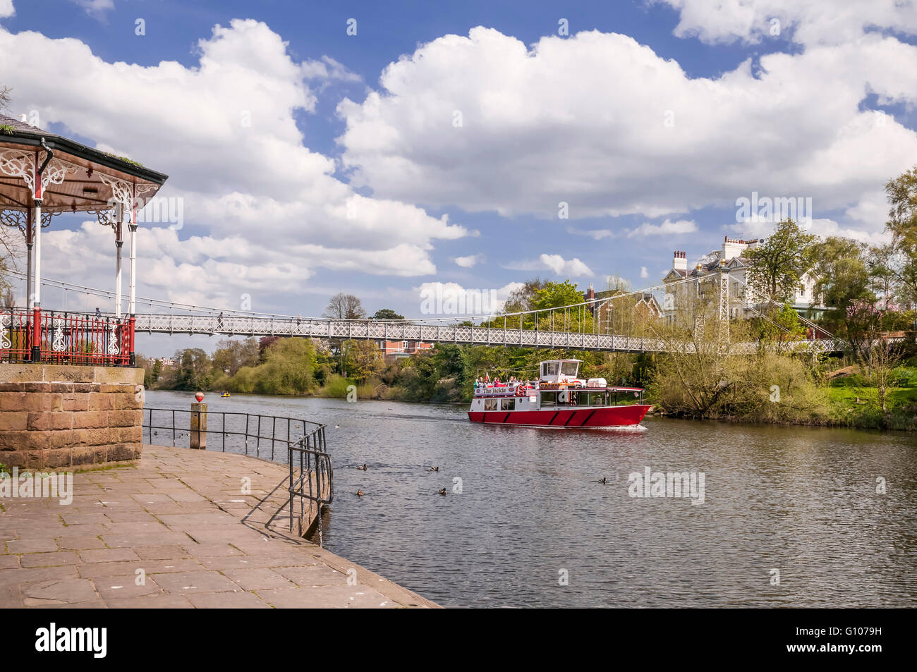 The river  Dee and pleasure boat at Chester. Cheshire. North West England. Also the Queens Bridge suspension footbridge. Stock Photo