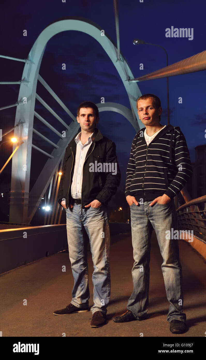 two guys standing on the night bridge and looking at camera Stock Photo