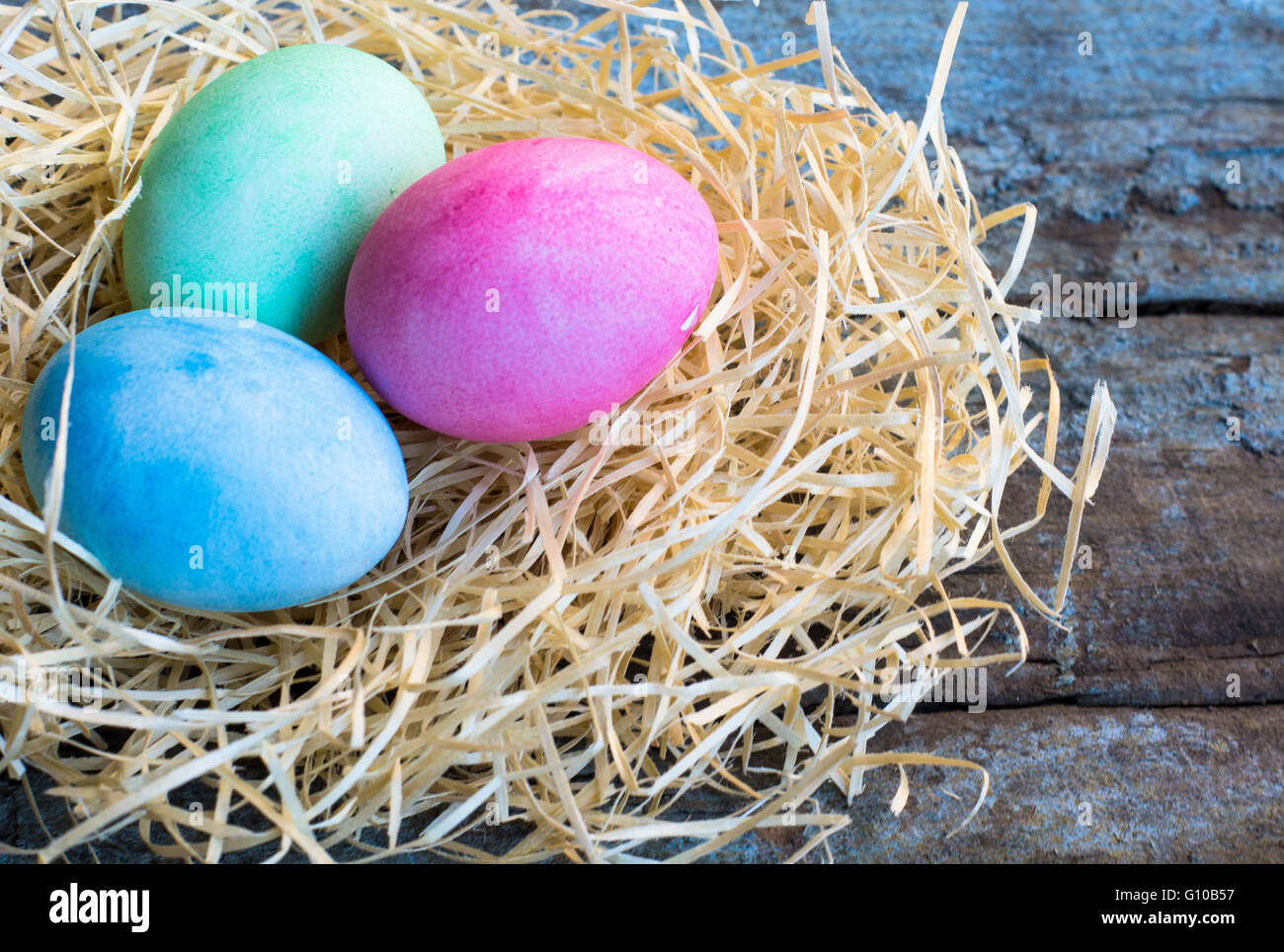 Easter eggs in a nest on rustic background Stock Photo - Alamy