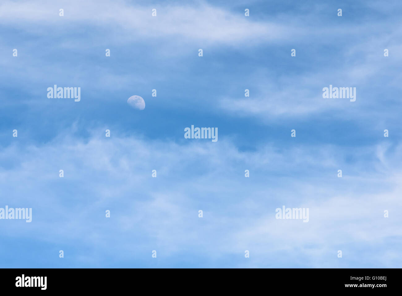 Moon Visible In Daylight Blue Sky With White Soft Clouds Stock Photo