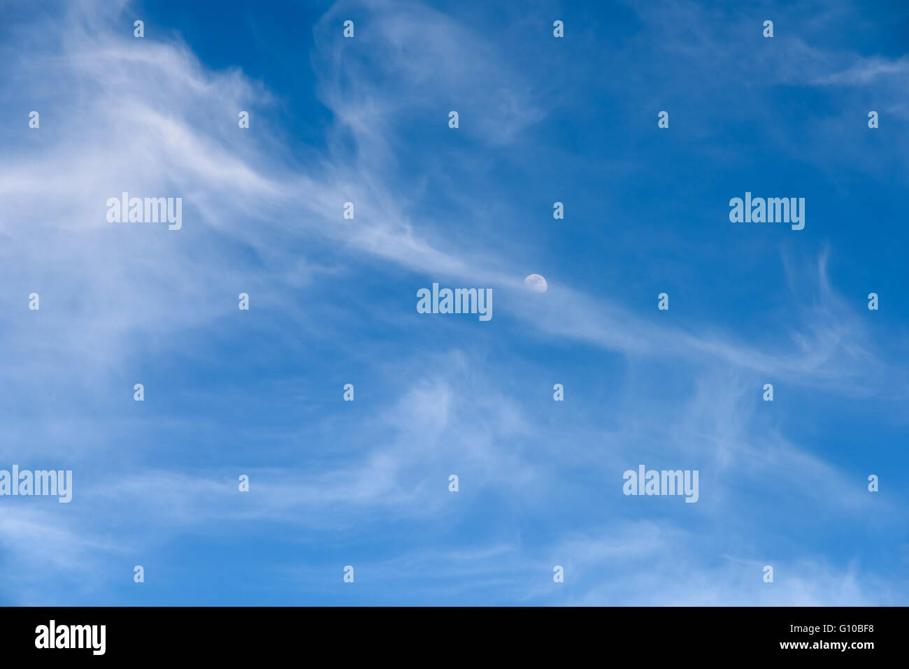 Moon Visible In Daylight Blue Sky With White Soft Clouds Stock Photo