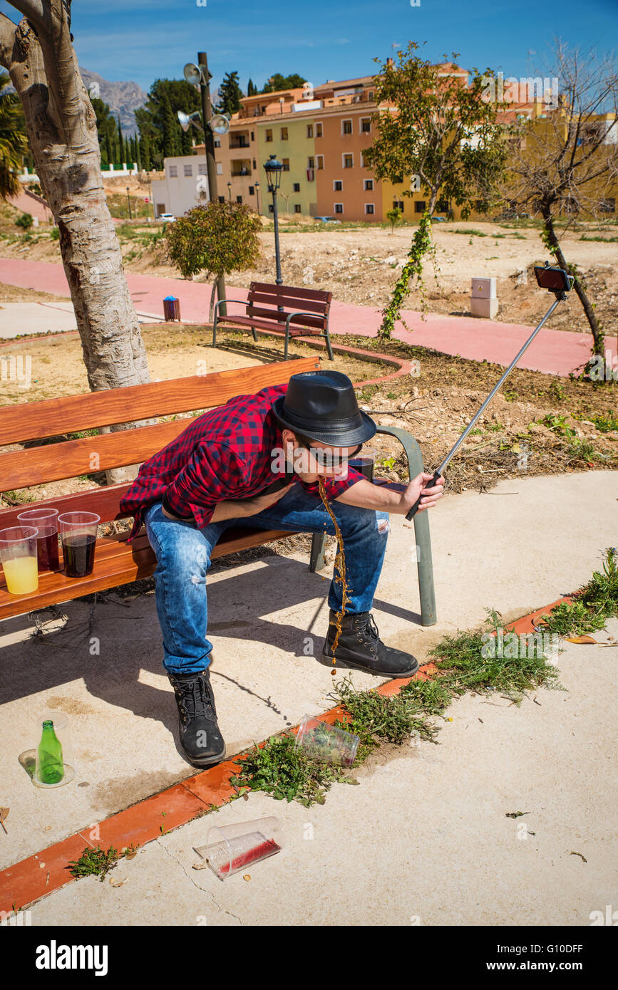 Guy throwing up on a park bench while taking a selfie Stock Photo Alamy