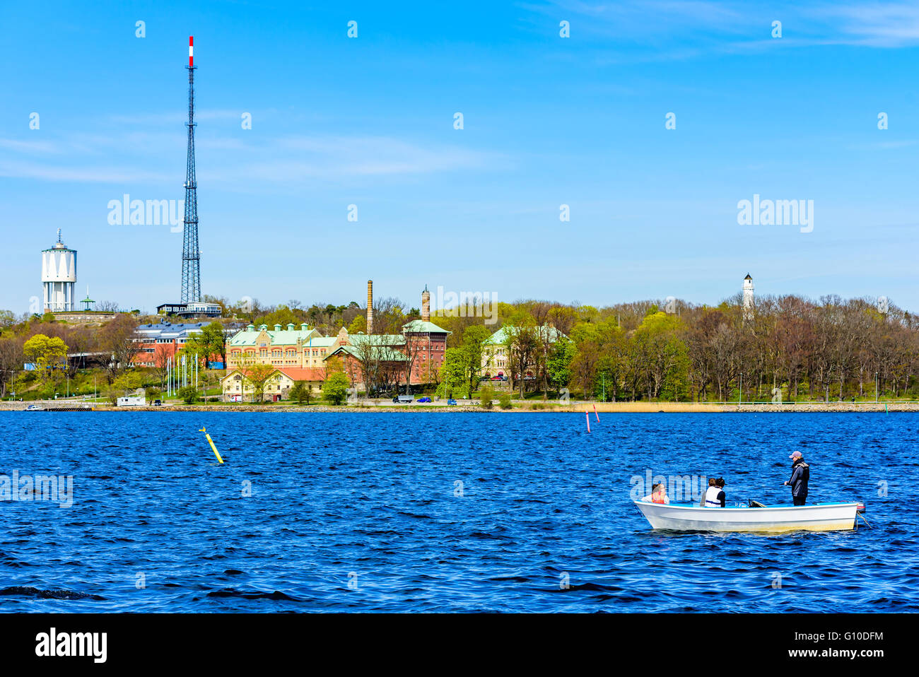 Karlskrona, Sweden - May 03, 2016: Scenic view with four persons in a small open motorboat fishing at sea with coastline in back Stock Photo