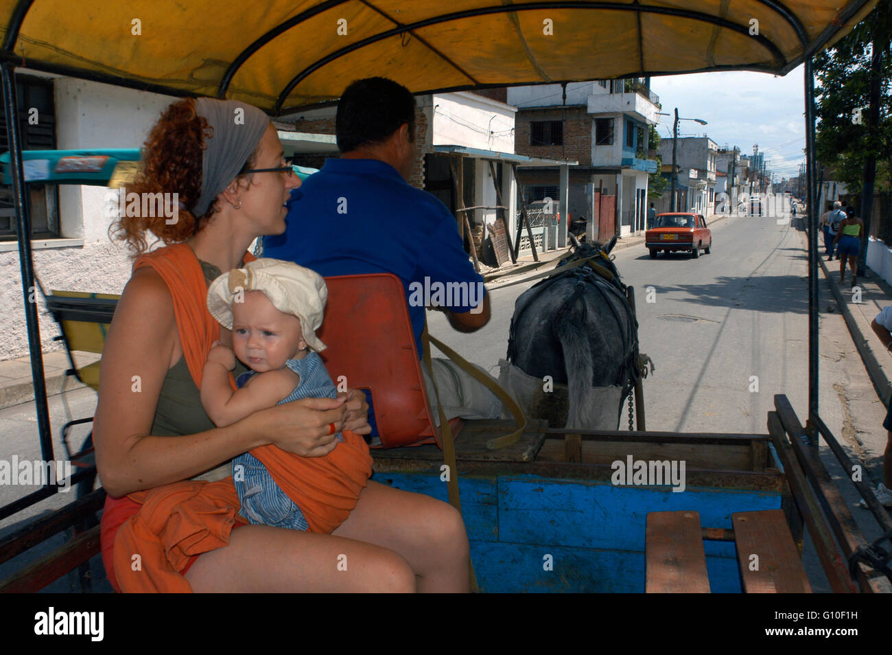 Tourist mother with her doughter inside a carriage. Horse and wagon on city street common transportation in Cuba Santa Clara, Cuba. Stock Photo