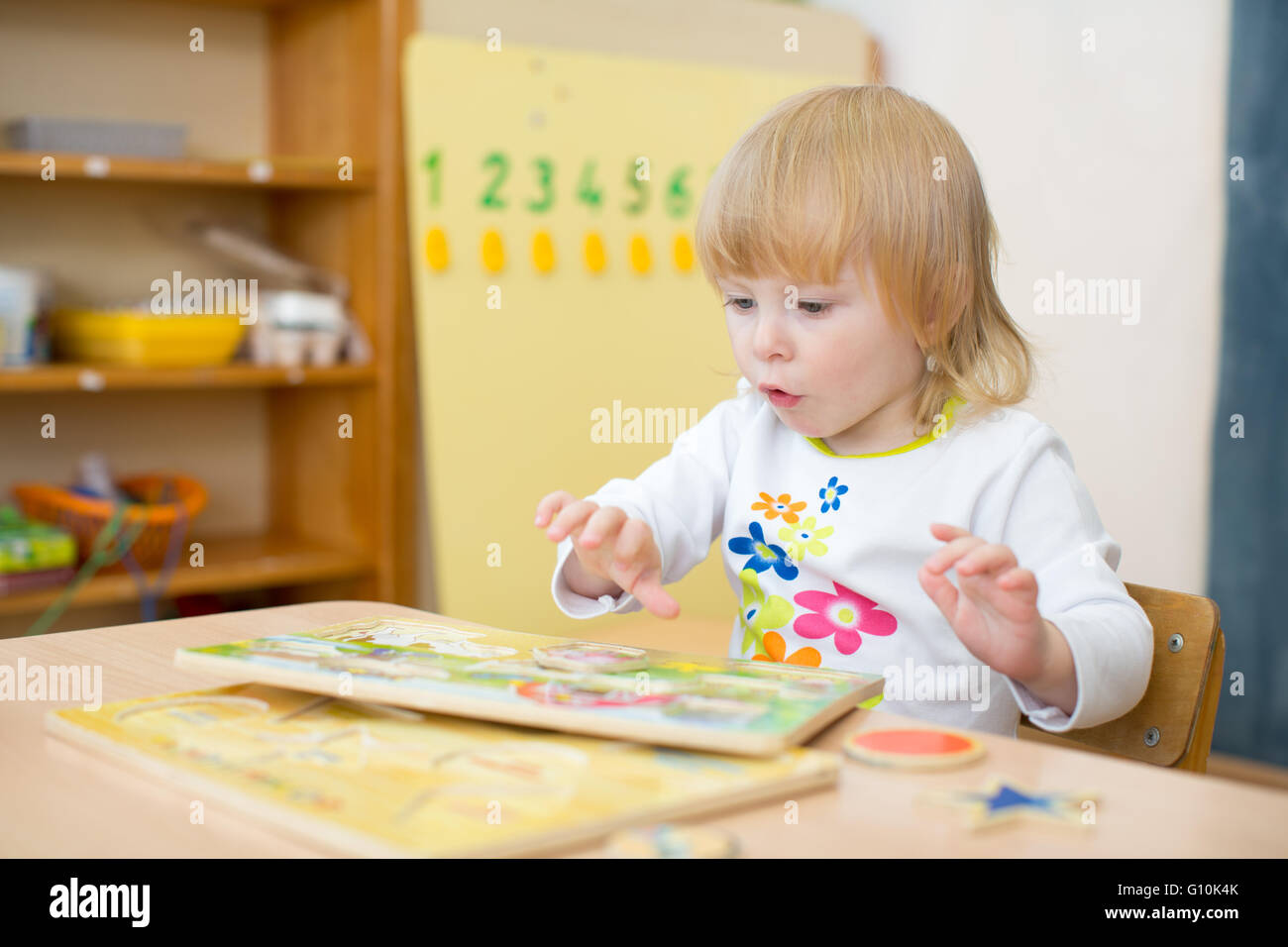 Pensive kid playing puzzle in kindergarten Stock Photo