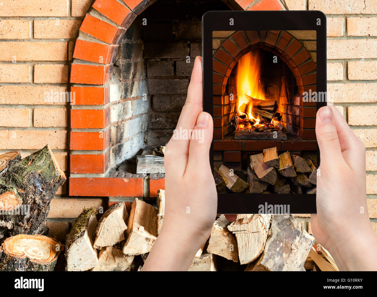 comfortable holiday concept - tourist photographs fire in fireplace on tablet pc Stock Photo