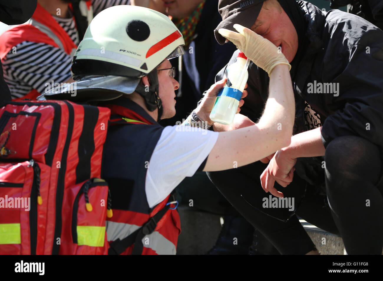 An anti-fascist protester is treated by a medic after being sprayed with CS gas by police. Thousands of anti-fascist campaigners held a counter protest against right-wing groups in Berlin. Hundreds of police lined the streets. Stock Photo