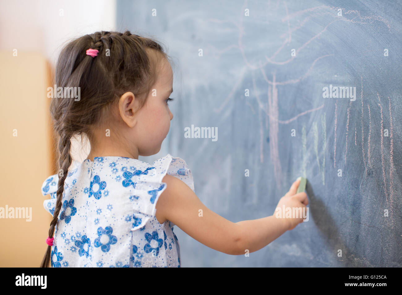 little girl side view near blackboard Stock Photo