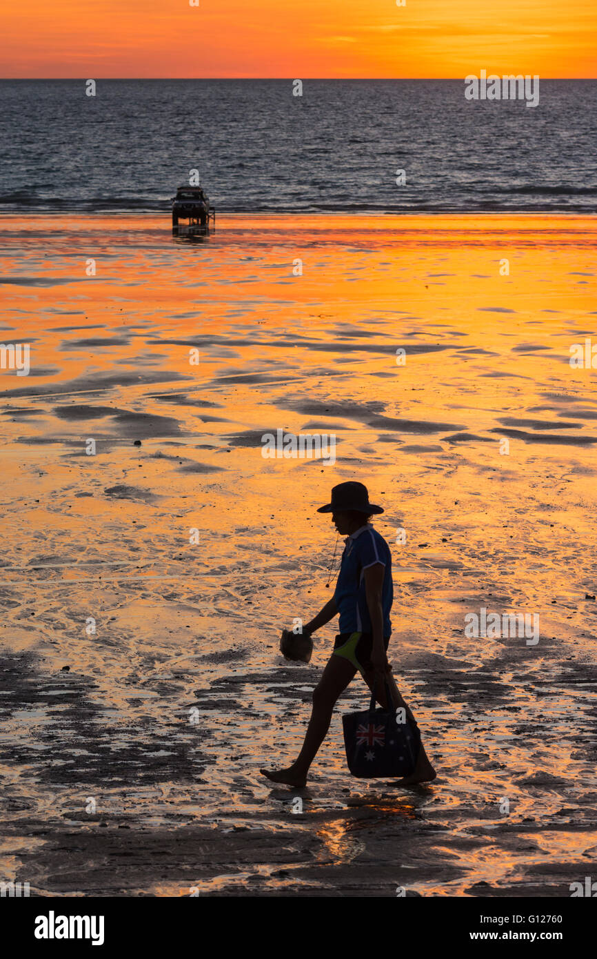 A person walking along Cable Beach at sunset  with a four wheel drive in the distance, Broome, Kimberley, Western Australia Stock Photo