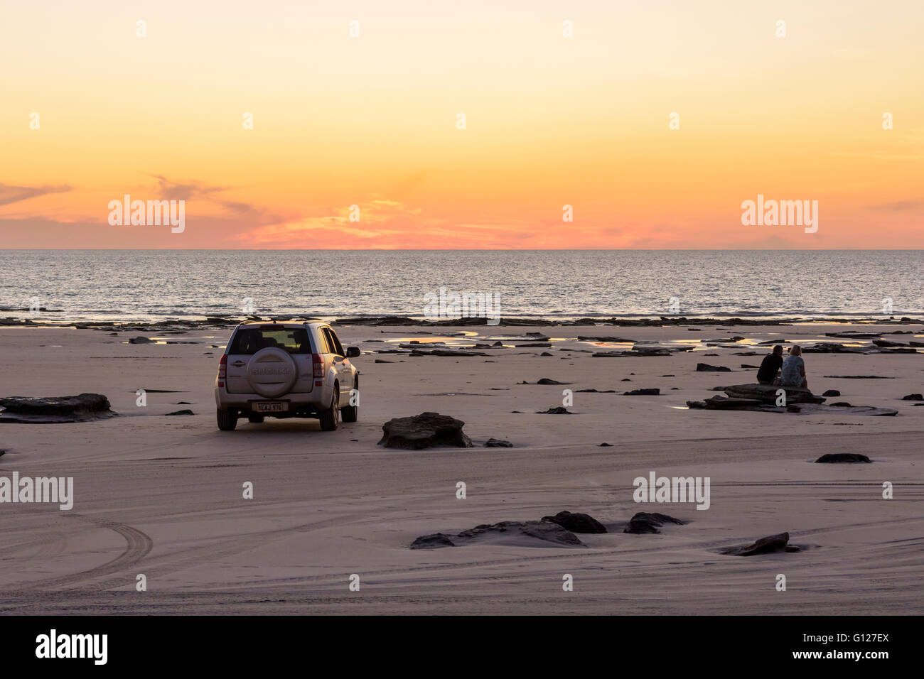 A couple watch the sunset near their four wheel drive vehicle on Cable Beach, Broome, Kimberley, Western Australia Stock Photo